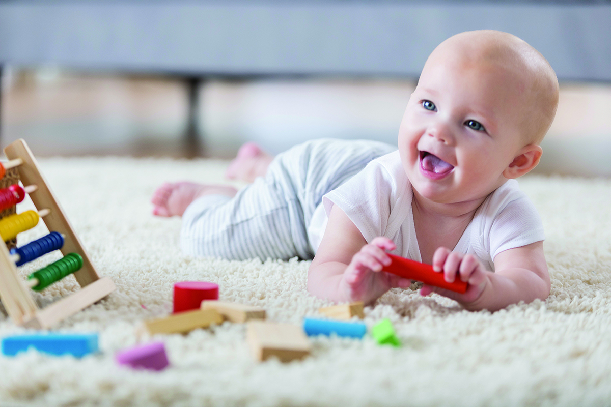 Cute baby sings with open mouth while playing with wooden blocks